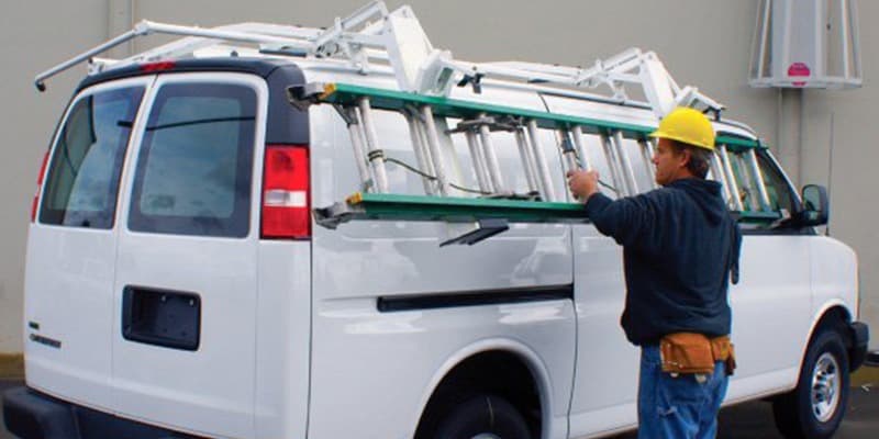 Man placing ladder into ladder rack attachment on work van