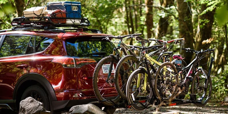 Red Toyota Rav4 using Yakima Cargo Carrier on roof and Yakima bike rack trailer hitch attachment carrying 4 bikes